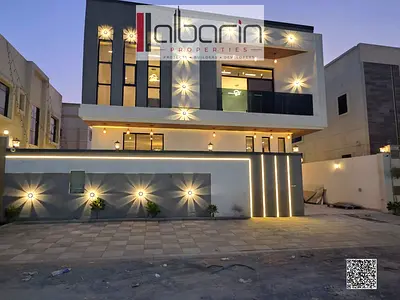 Independent villa for sale in Al Helio 2, Ajman; features 5 master bedrooms and a modern facade—all fees included.