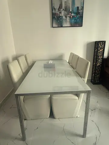 White glass dining table with 6 white upholstered chairs