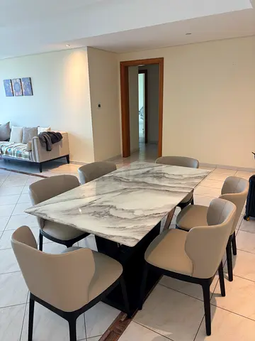 Marble-top dining table with 6 beige upholstered chairs