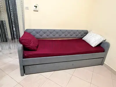Grey upholstered daybed with pull-out trundle and mattress