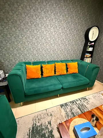 Green velvet 3-seater sofa with gold legs and orange cushions plus one big orange chair