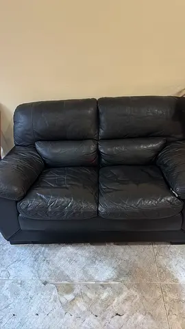 Two-seater black leather sofa in good used condition