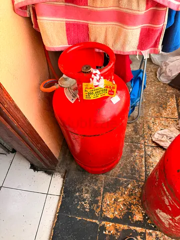 Full red LPG gas cylinder with regulator hose