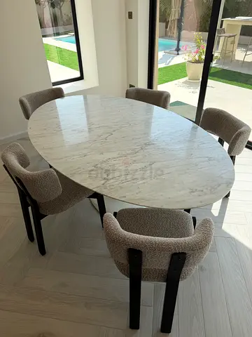 Oval marble dining table with 5 upholstered boucle chairs
