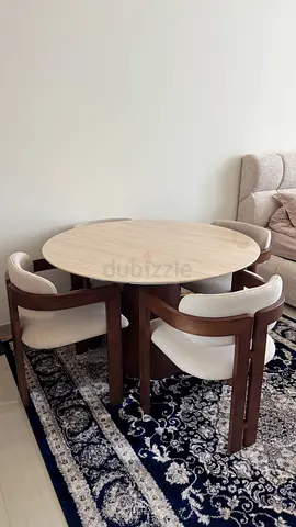 Round wooden dining table with 4 upholstered chairs. A small chip on the edge of the table.
