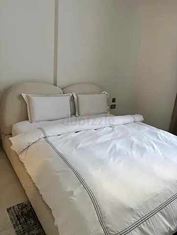 Modern upholstered double bed with curved headboard - beige