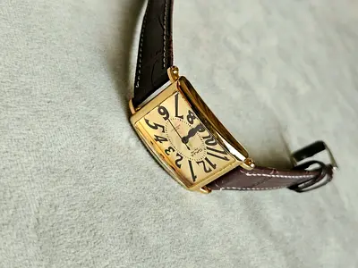 Gold-tone rectangular analog wristwatch with brown leather strap
