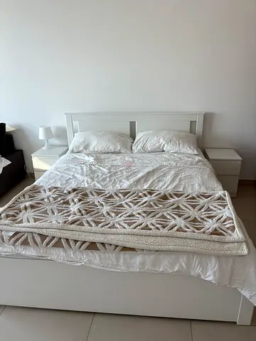 White wooden king-size bed frame with headboard and two nightstands