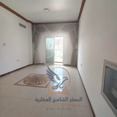 One-bedroom apartment with a living room, balcony, and central air conditioning for rent in Al Rashidiya 3, Ajman, behind Grand Mall.