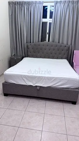 Grey upholstered queen bed with 2 night stand and mirror drawers storage base and headboard