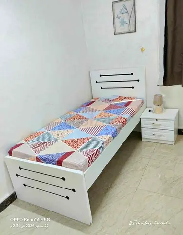 Single white wooden bed with mattress and bedside table