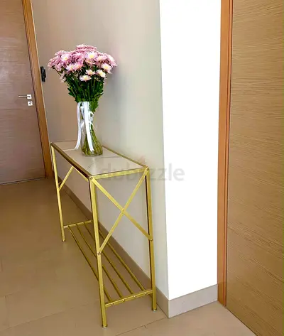 Slim gold metal console table with glass top