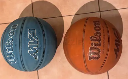 Two used Wilson basketballs — one orange, one blue