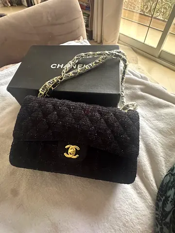 Black tweed quilted Chanel-style shoulder bag with chain strap.