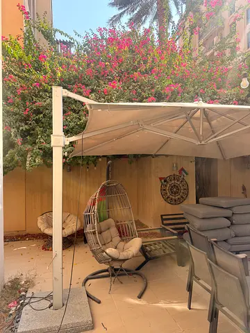 Outdoor large parasol with a freestanding side pole light inside and a beige/taupe fabric canopy.