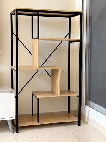 Industrial-style open shelving unit with staggered wooden shelves and black metal frame