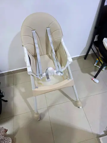 Lightweight beige baby high chair with safety harness